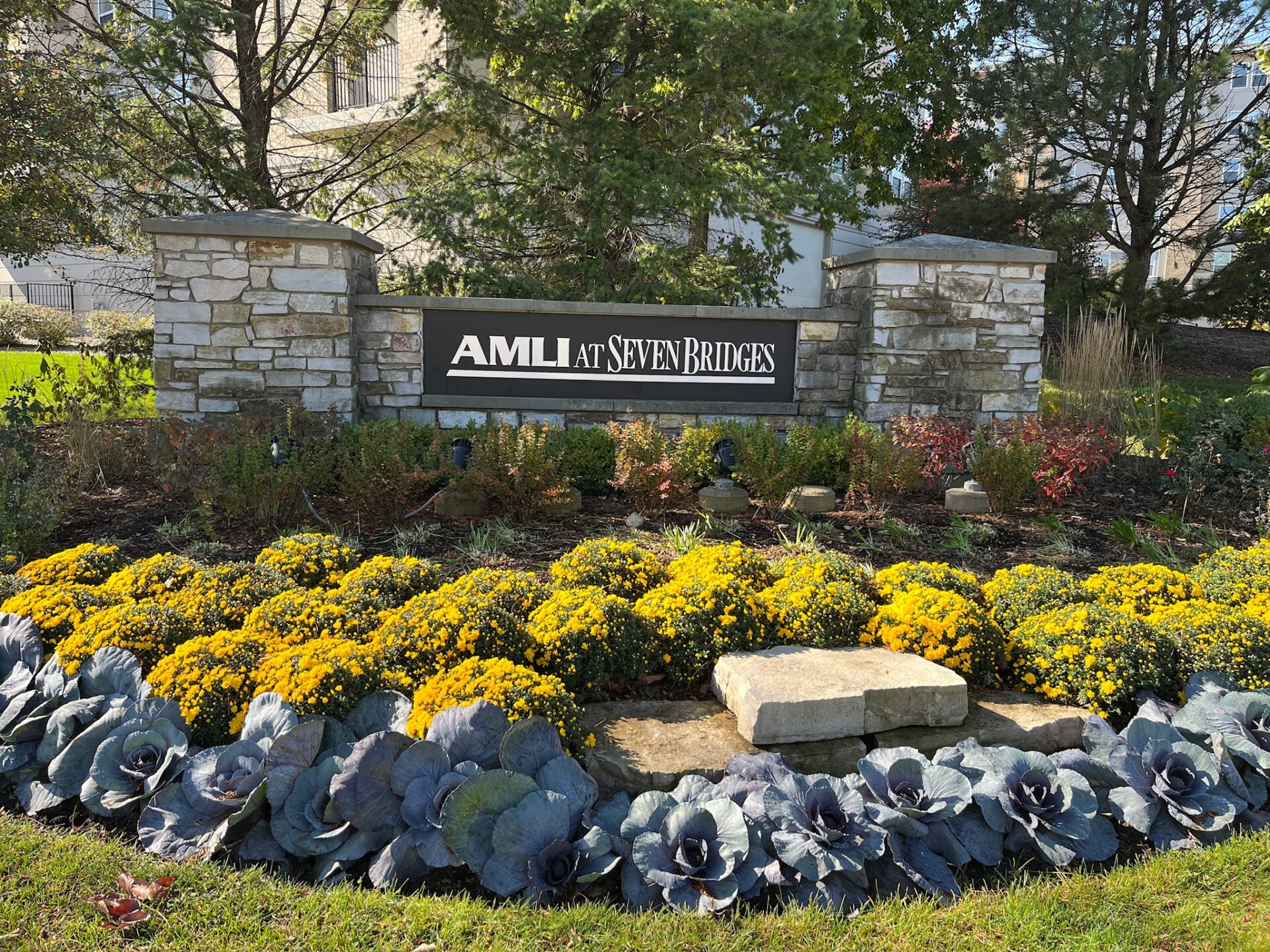 The image shows a landscaped stone sign for 