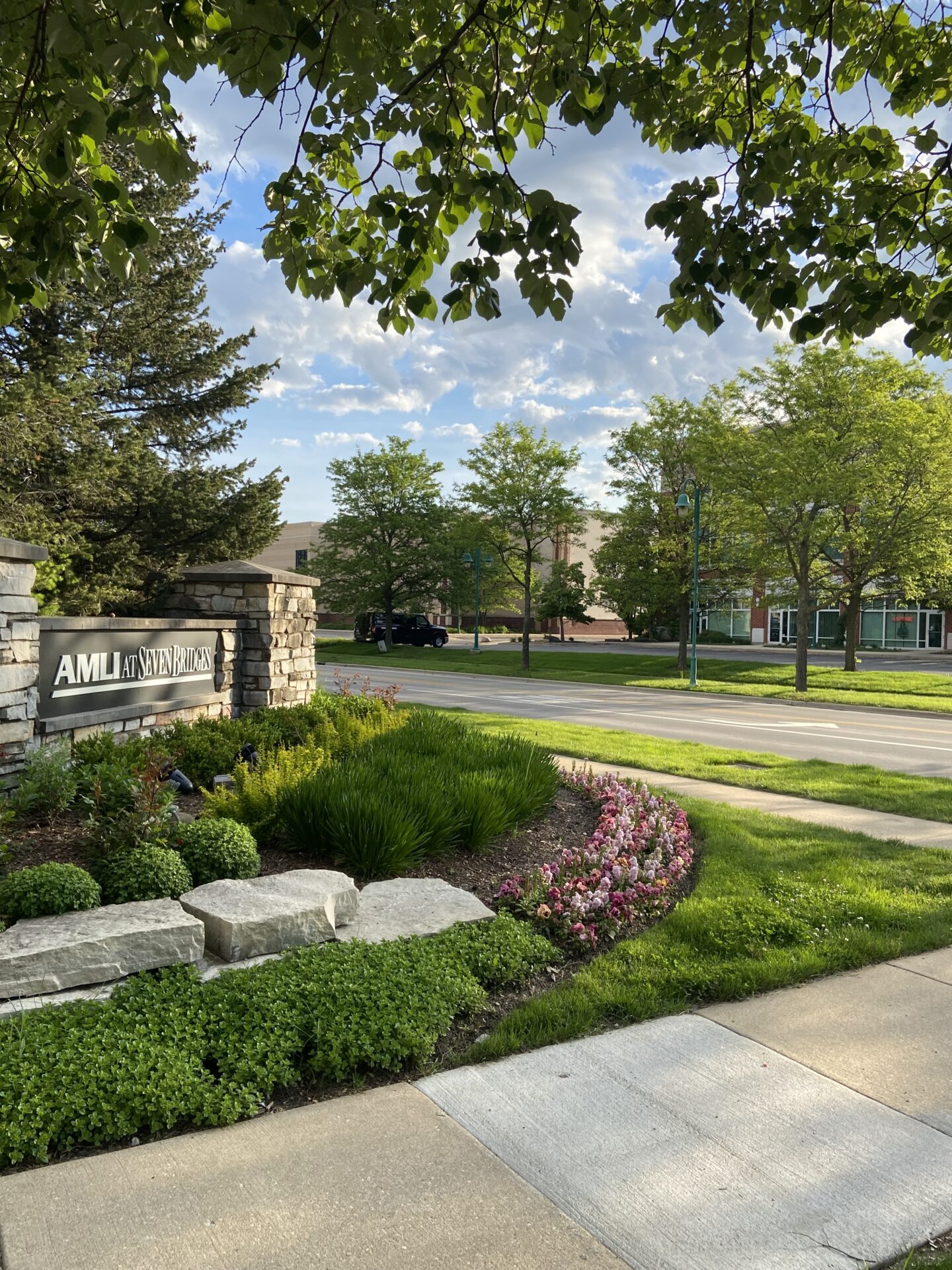 Urban scene with landscaped greenery, stone signage reading 